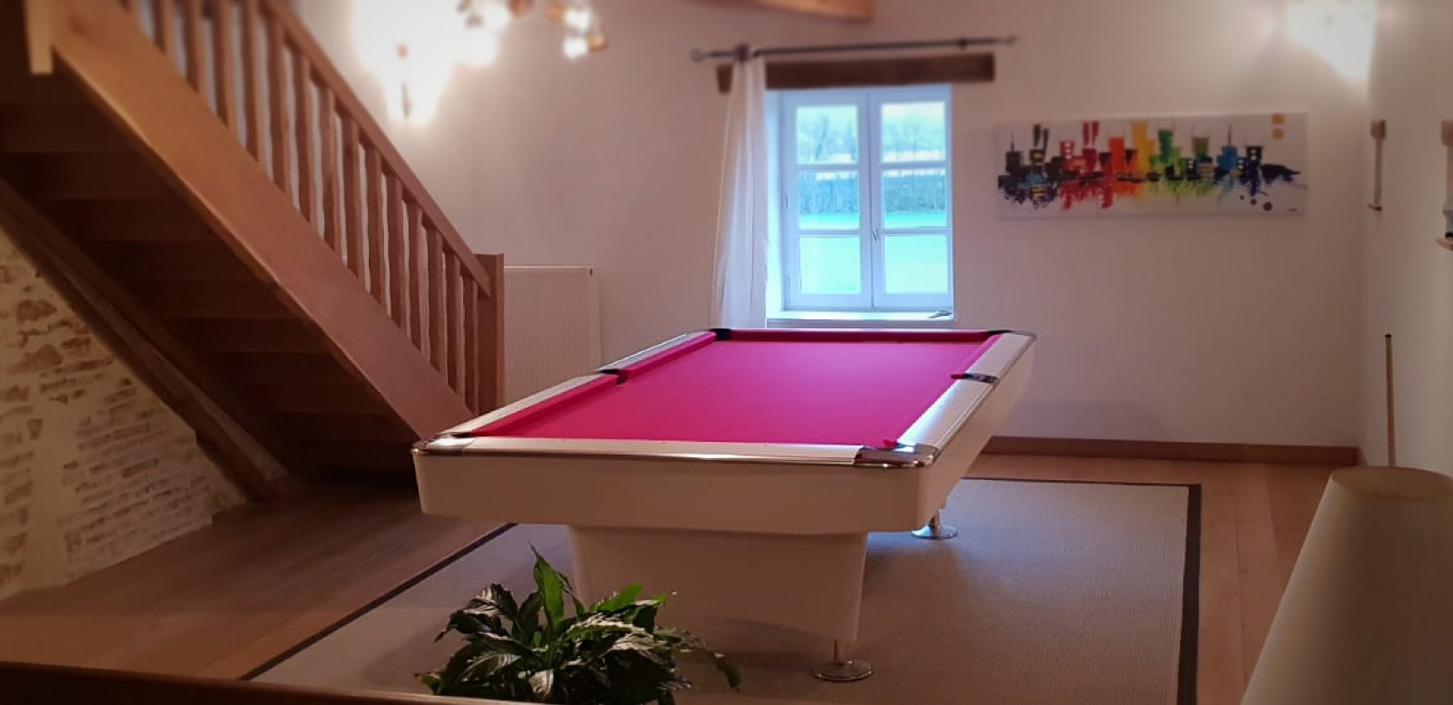 Billard année 60 blanc laqué monté d'un tissu rouge dans sa salle au pied de l'escalier prêt à accueillir les billes de toutes les couleurs du jeu de billard américain